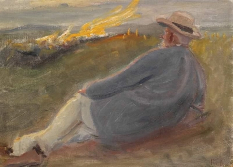 Ein Mann mit Strohhut, der in den Dünen liegt und ein Feuer beobachtet