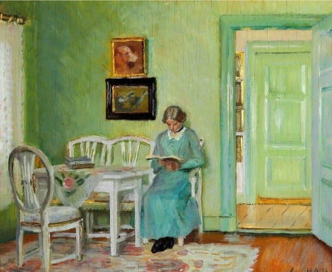 Interiör från ett grönt vardagsrum med en ung kvinna som läser 1916
