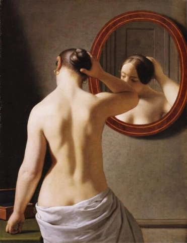 Eine nackte Frau, die sich vor einem Spiegel die Haare frisiert