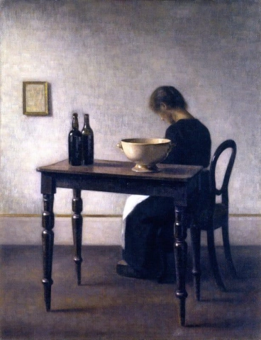 Interiør med kvinne som sitter ved et bord 1910